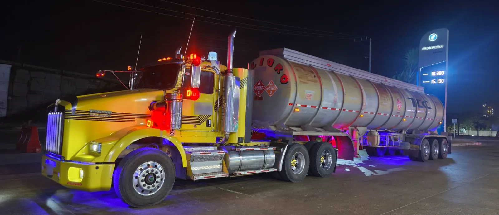 Tractocamión Kenworth de TLC con carrotanque, iluminado de noche en la vía