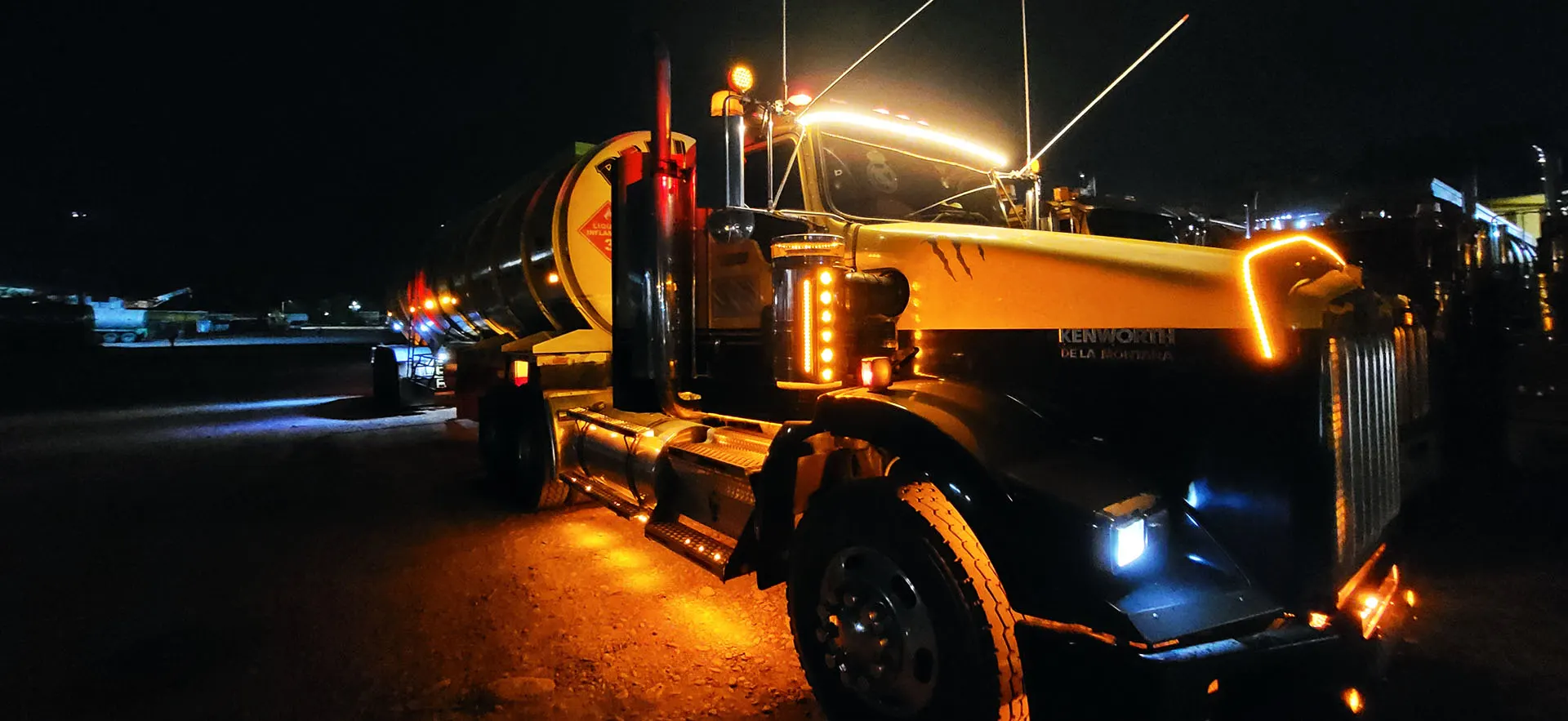 Tractocamión cisterna de TLC con luces encendidas durante una operación nocturna